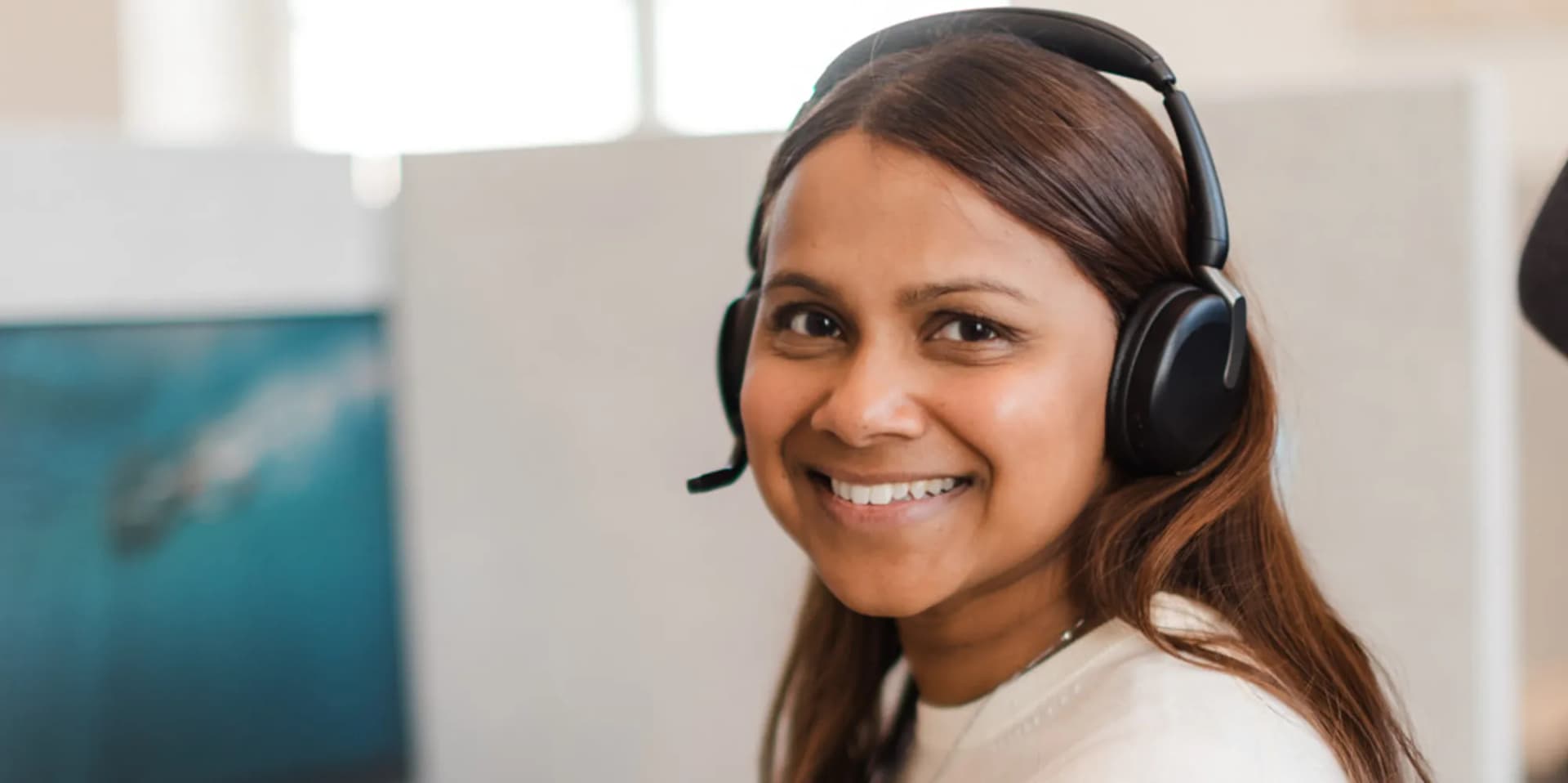 En kvinna med headset framför en dator.