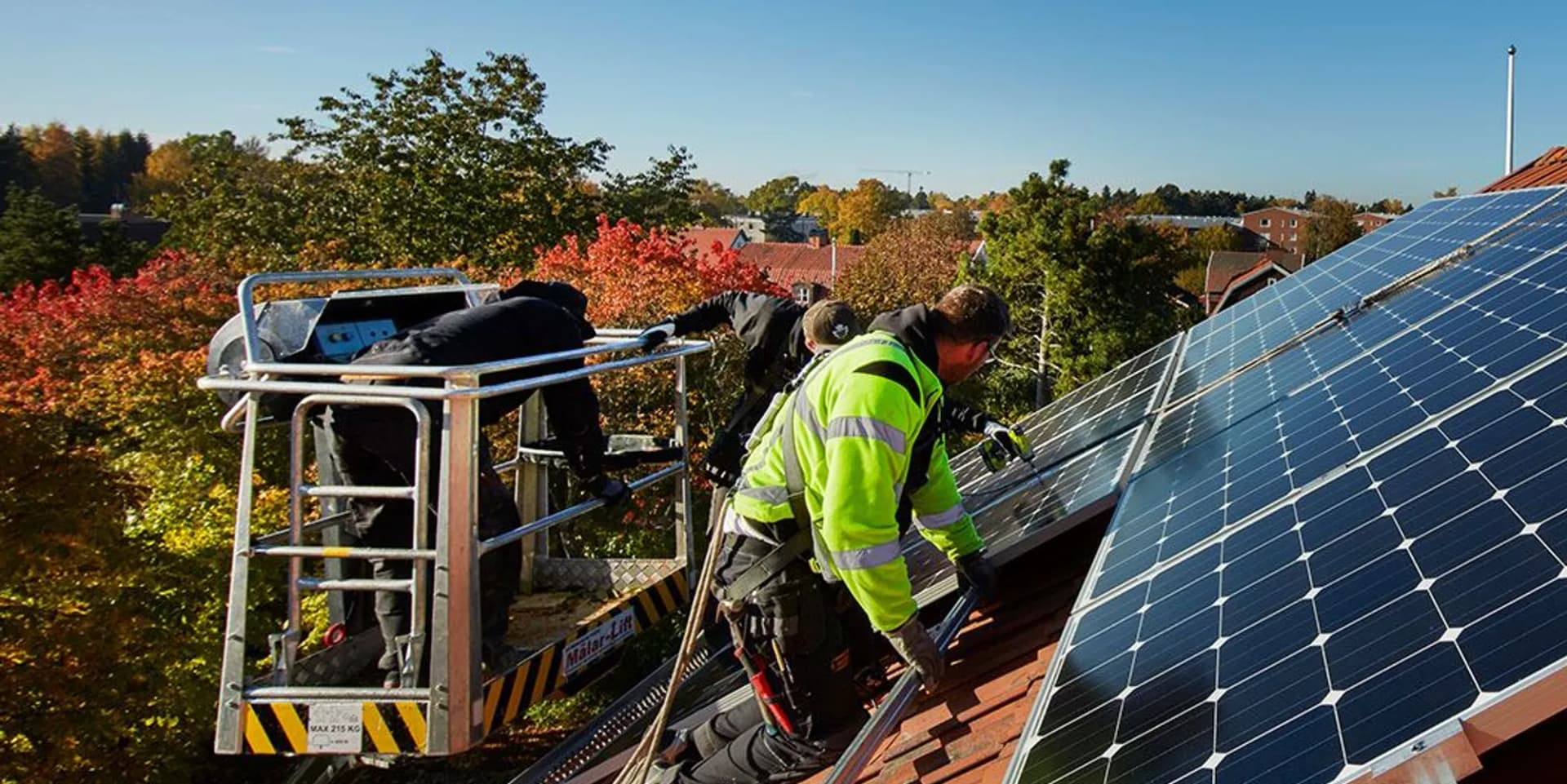 En man installerar solceller på taket till ett hus.