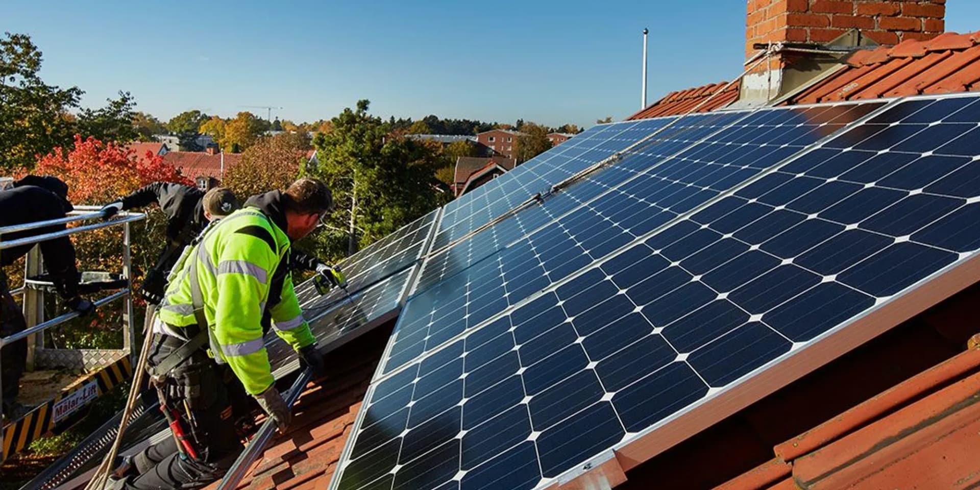En man installerar solceller på taket till ett hus.