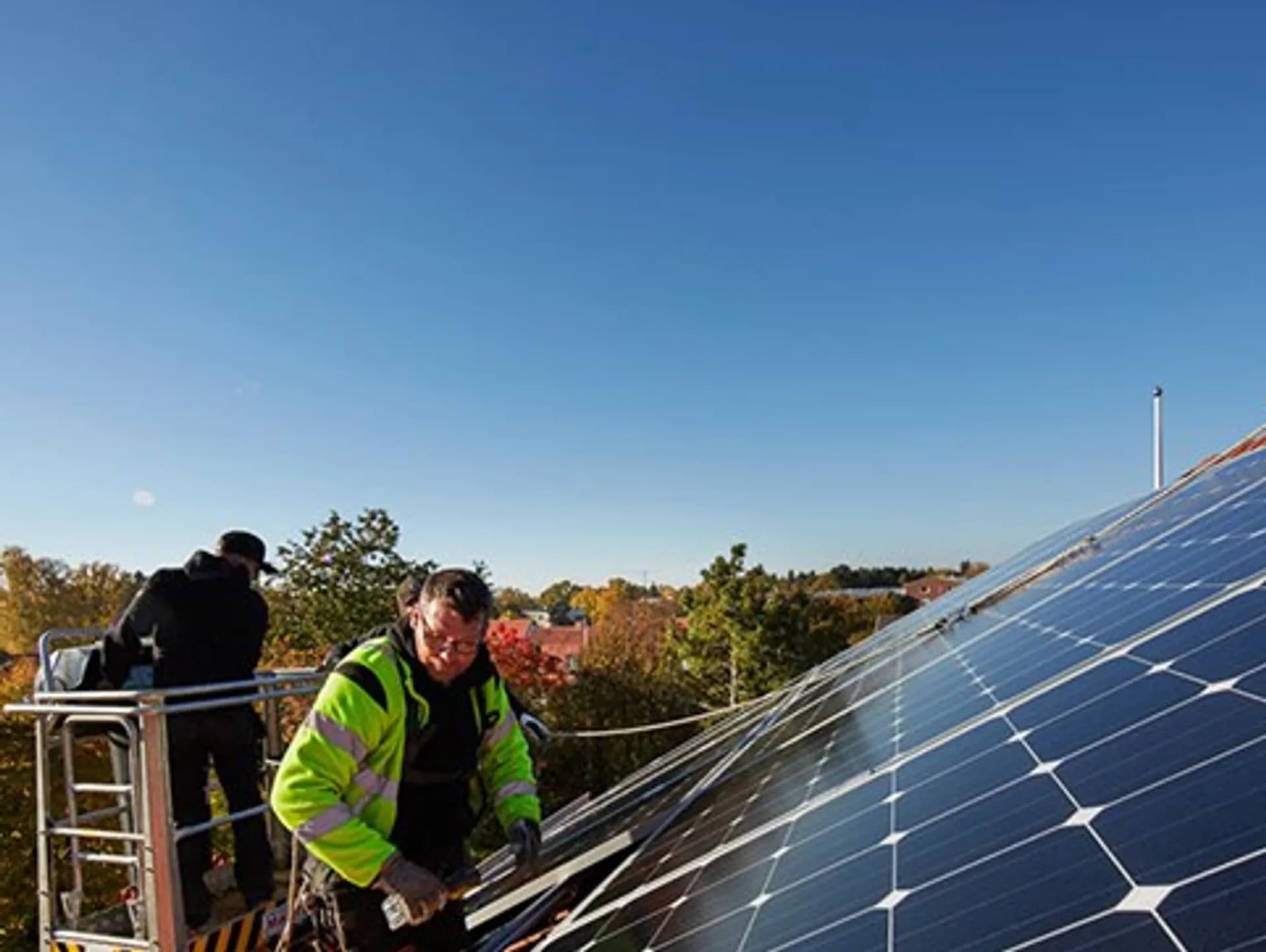 En man installerar solceller på taket till ett hus.