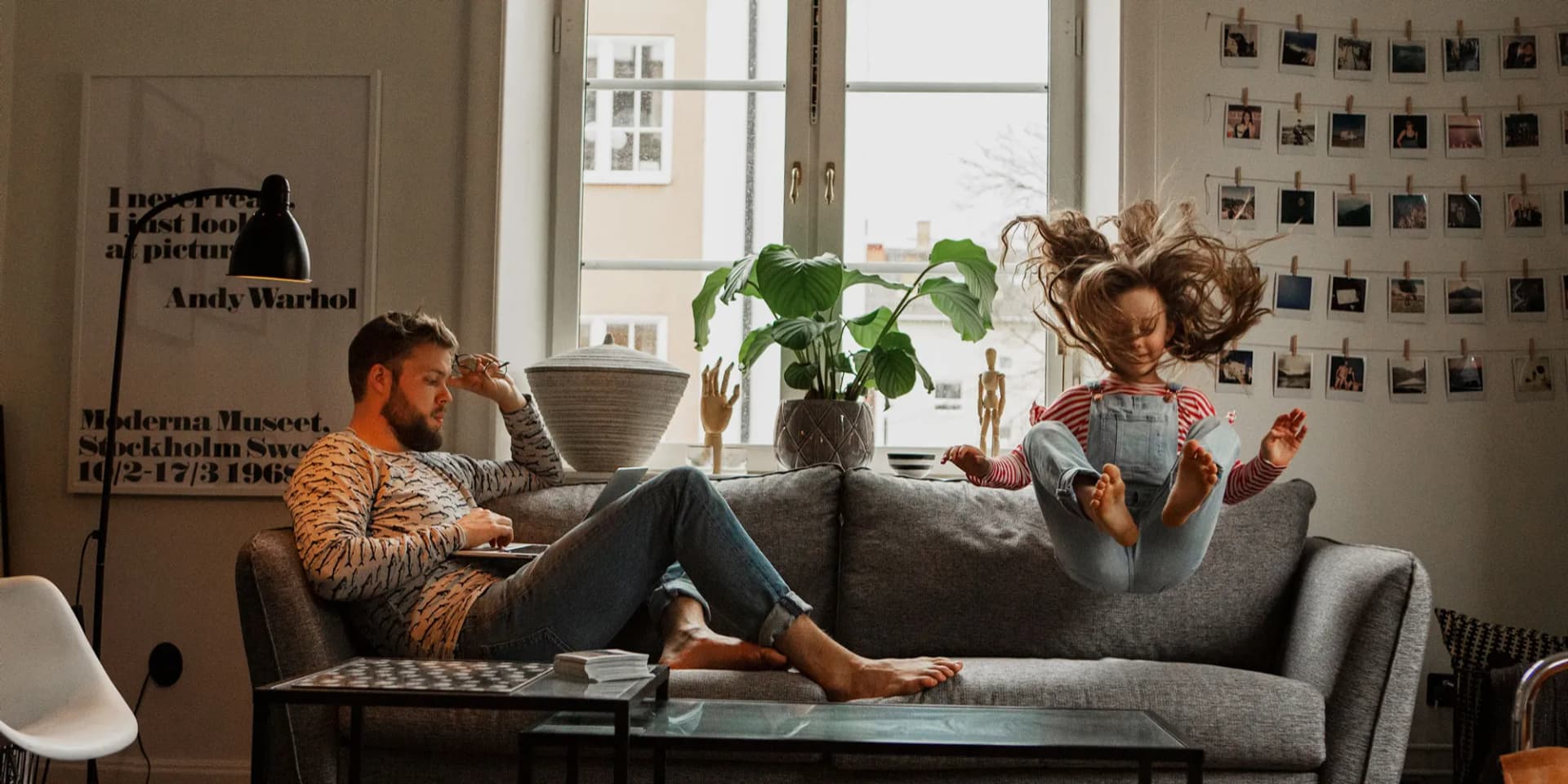 En man och ett barn sitter på en soffa i ett vardagsrum.