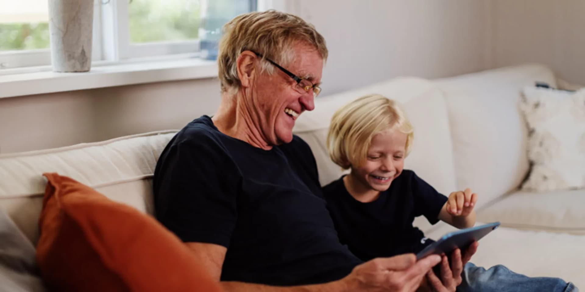 En man och ett barn sitter i en soffa.