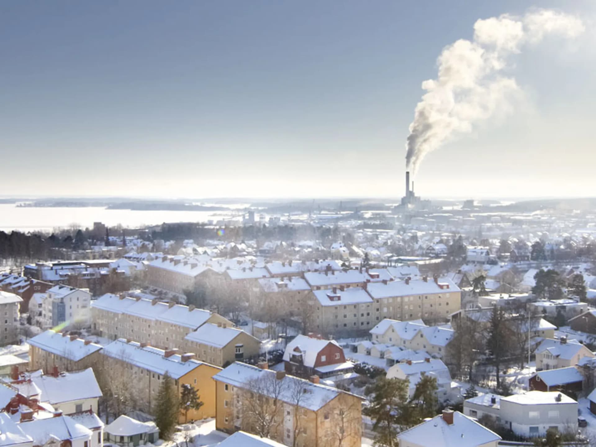 En utsikt över en snöig stad med en fabrik i fjärran.