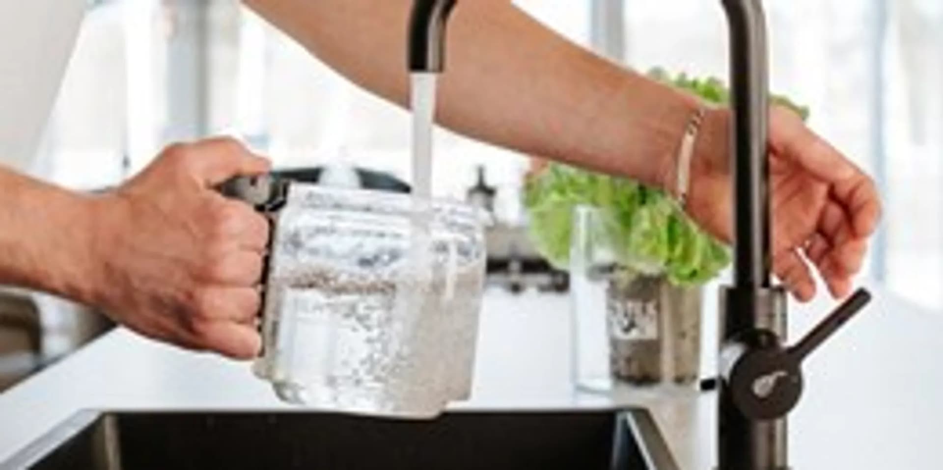 En man häller upp vatten i ett glas.