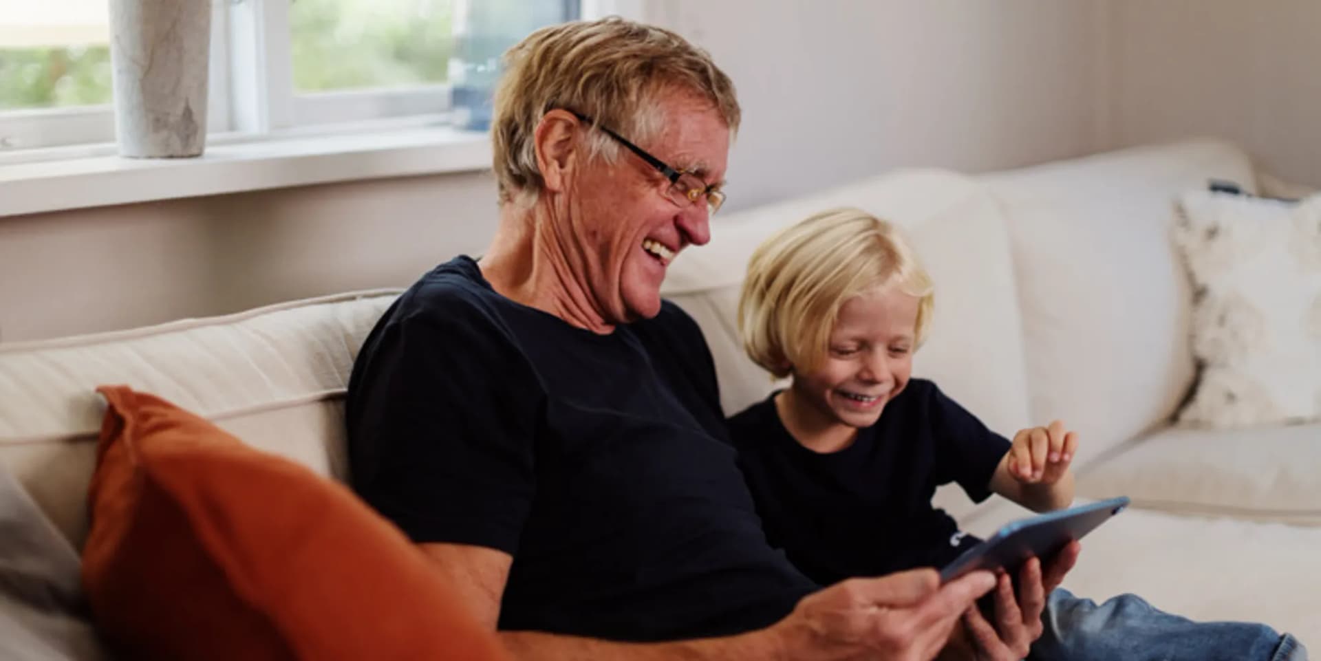 En man och ett barn sitter i en soffa.