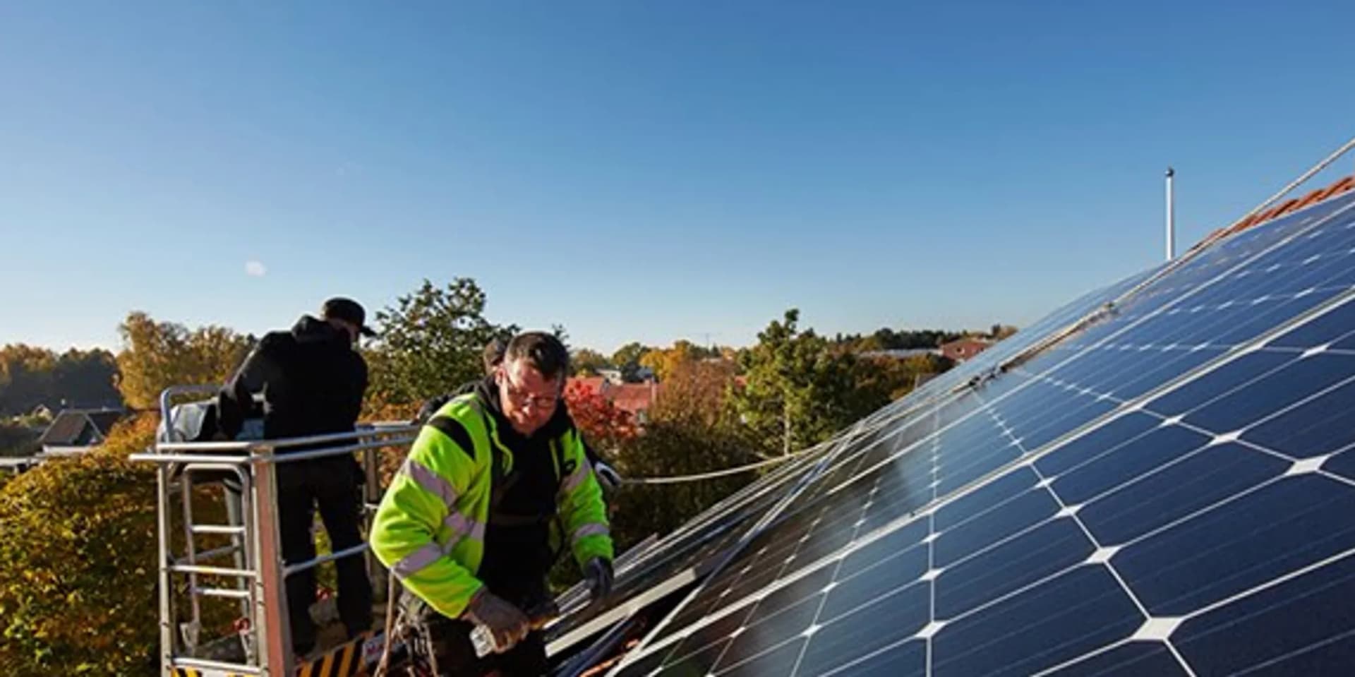En man installerar solceller på taket till ett hus.