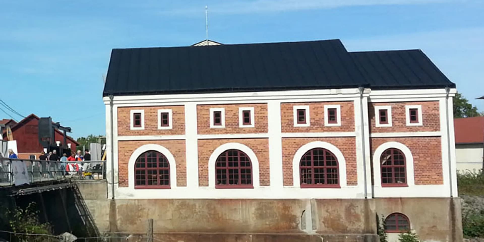 En röd tegelbyggnad som ligger intill en flod.