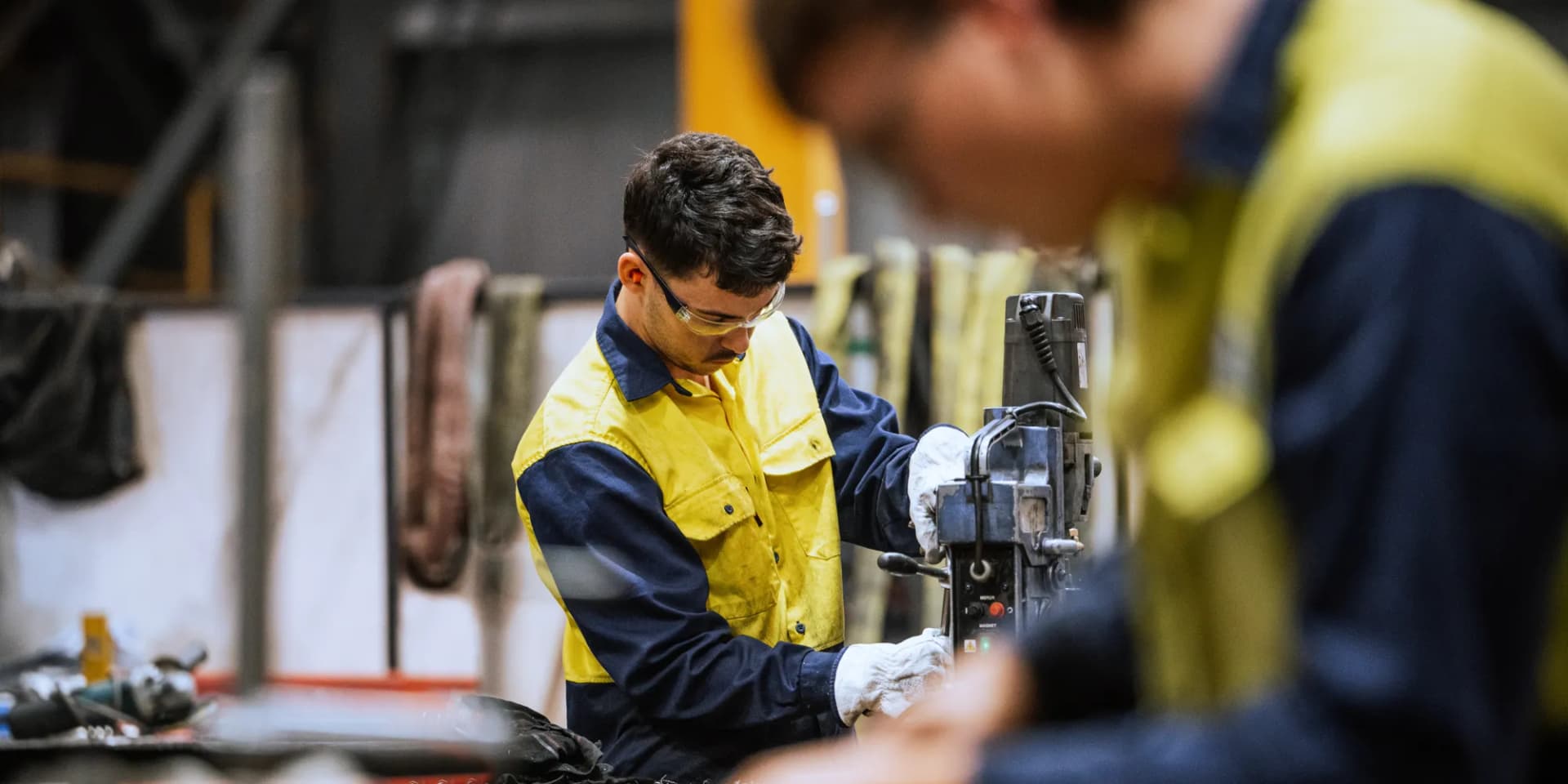 Två män som arbetar vid en maskin i en fabrik.