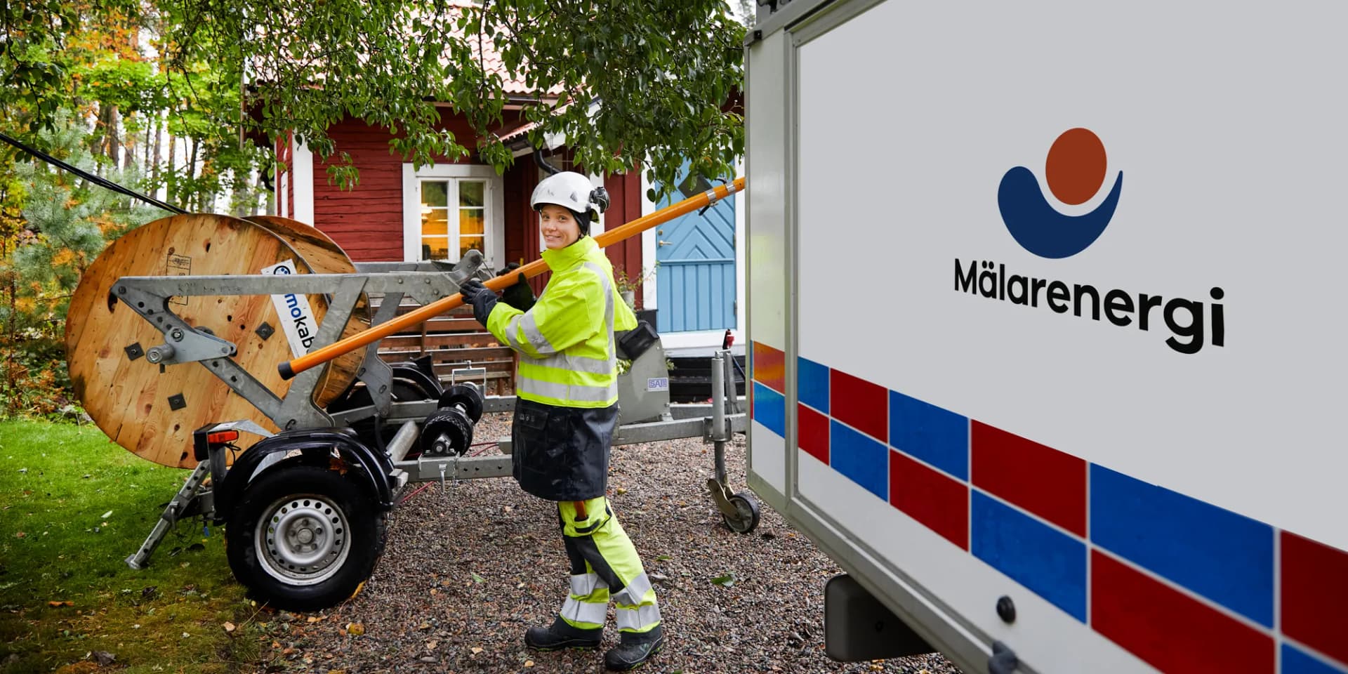 En kvinna i gul jacka arbetar med elledningar.
