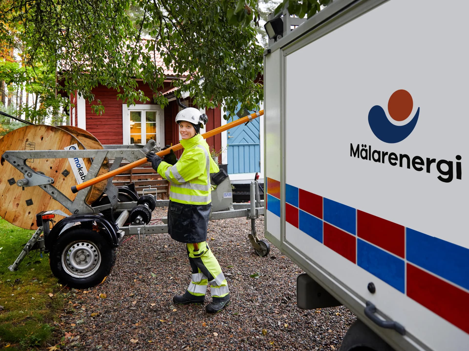 En kvinna i gul jacka arbetar med elledningar.