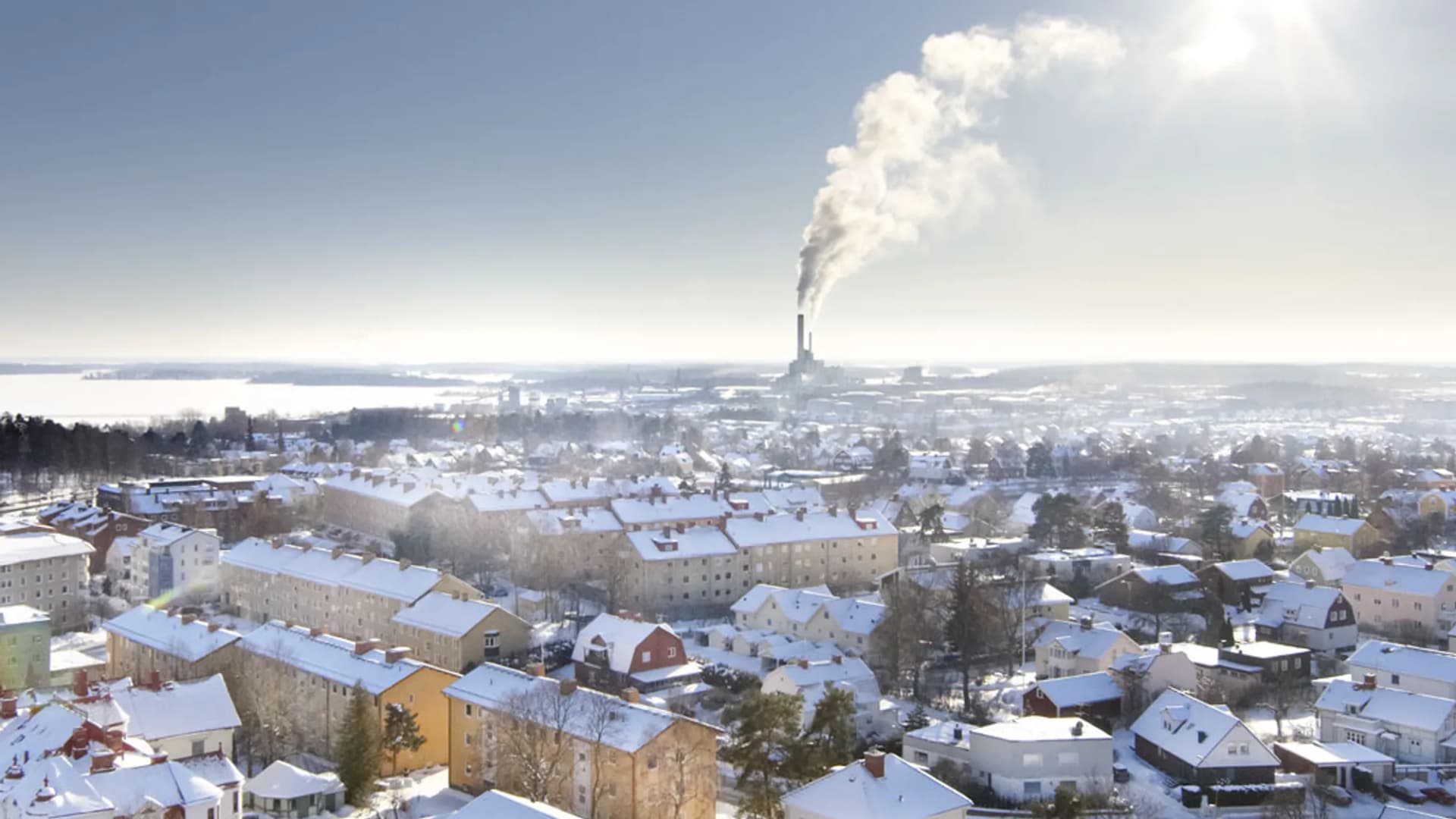 En utsikt över en snöig stad med en fabrik i fjärran.