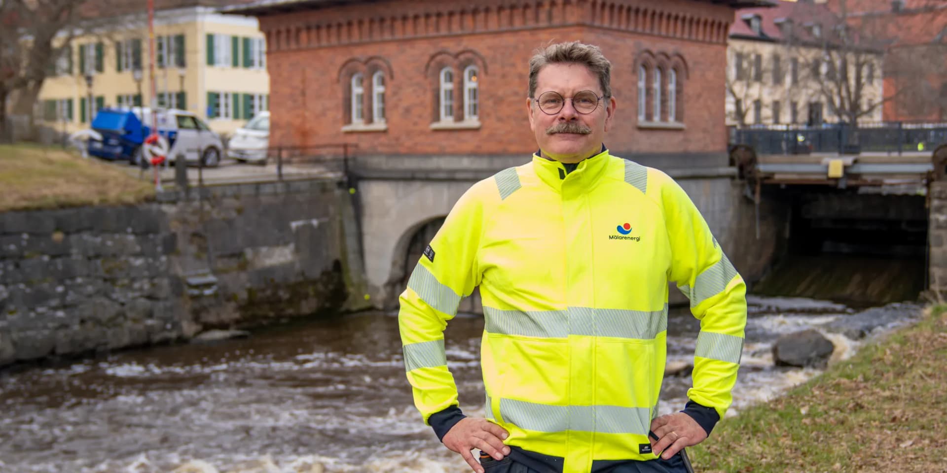 En man i en gul jacka som står framför en å.