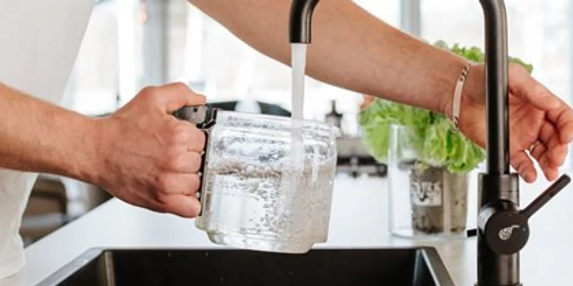 En man fyller ett glas med vatten.