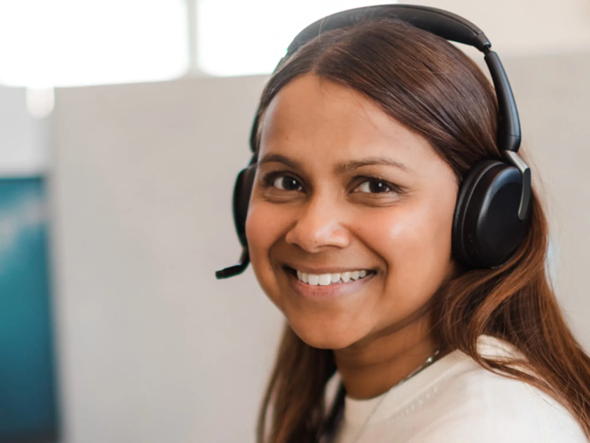 En kvinna med headset framför en dator.