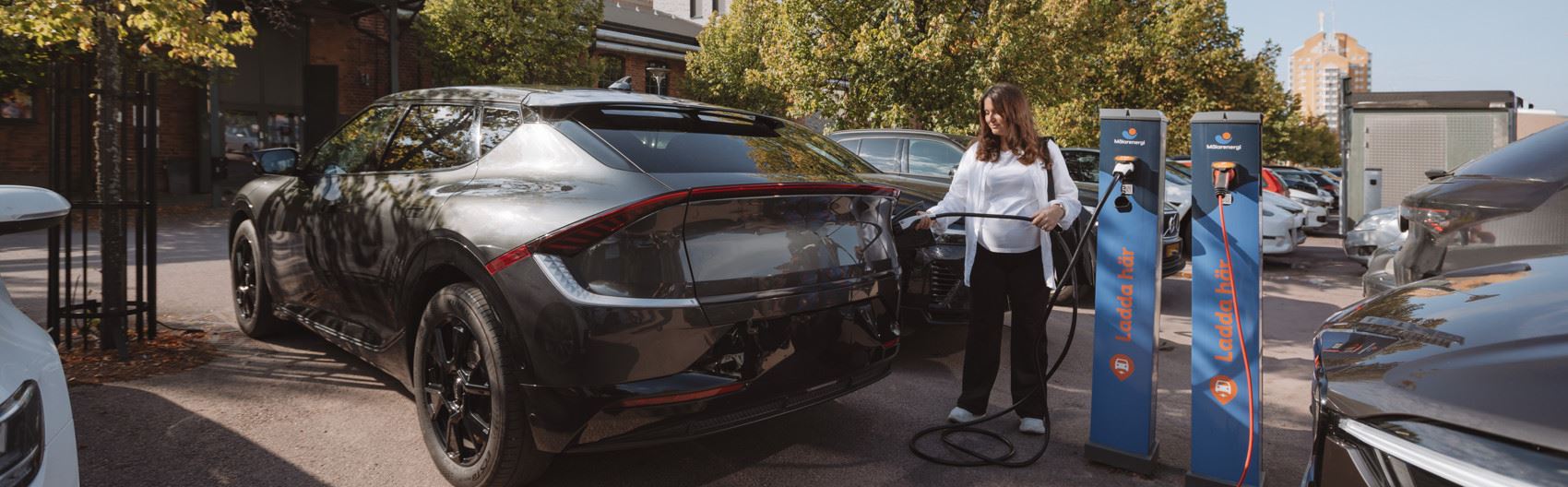 Kvinna laddar elbilen på Kopparlunden