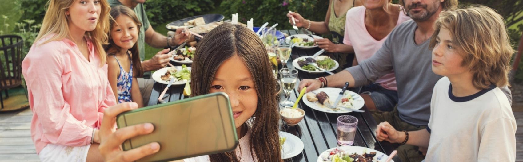 Familj äter middag och barn tar en bild med telefonen