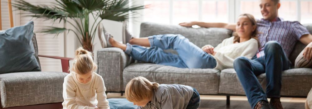 En familj som kopplar av i vardagsrummet medan barnen leker i ett hus uppvärmt med fjärrvärme.