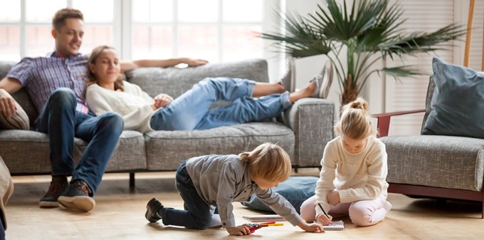 En familj samlad i vardagsrummet medan barnen leker