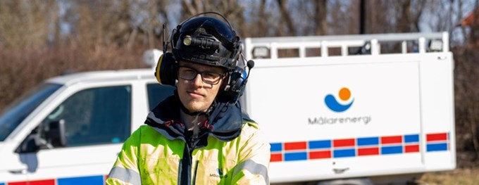 En man i varselkläder står framför en bil. 