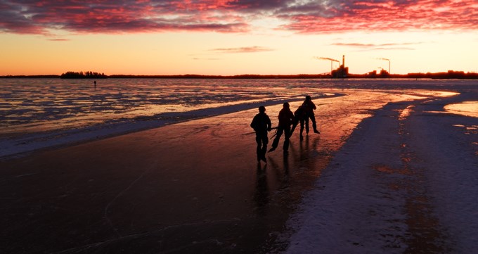 Skridskoåkare på Mälaren i solnedgång.