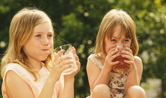 Barn sitter och dricker svealands godaste vatten en solig dag.