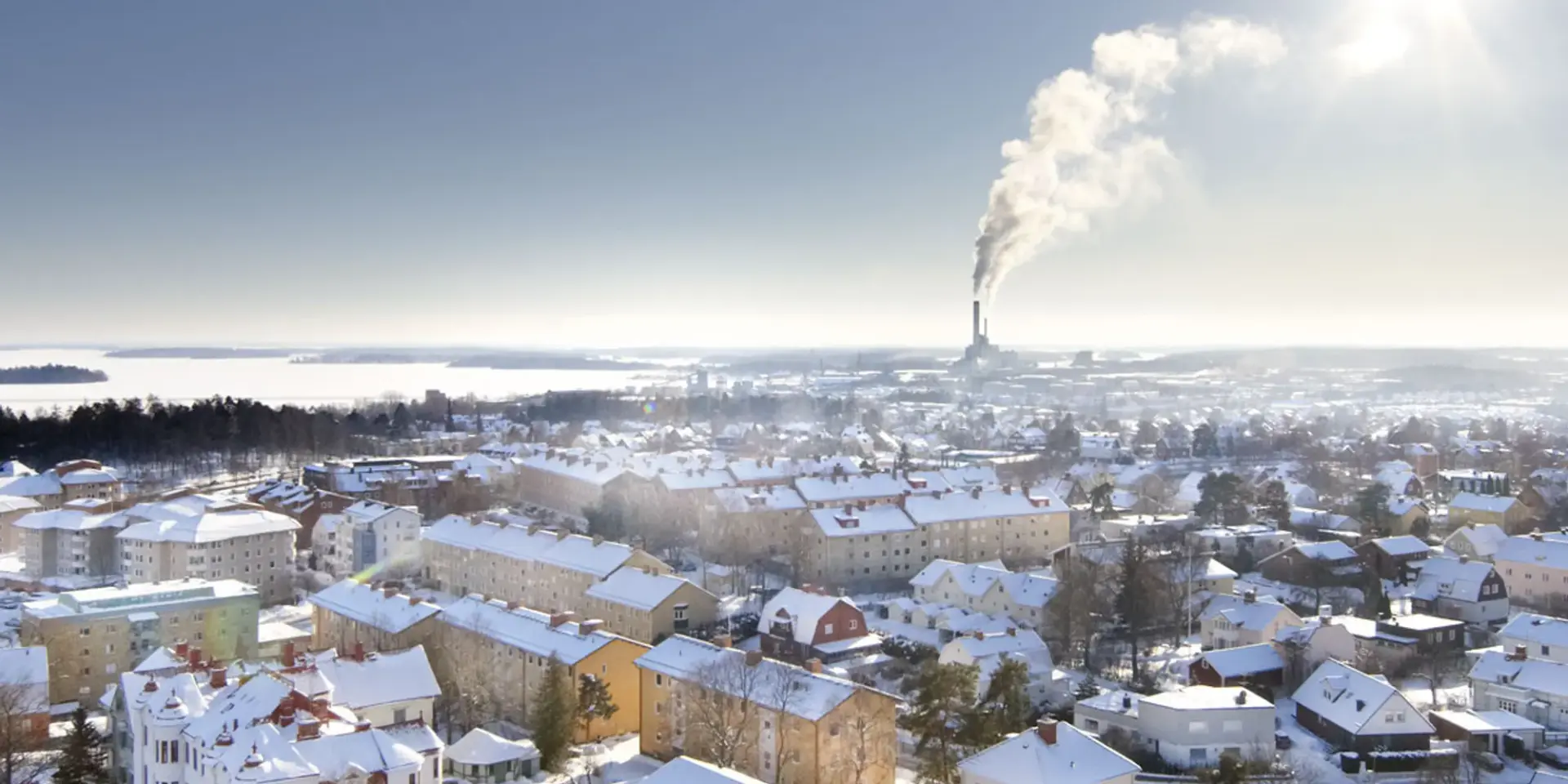En utsikt över en snöig stad med en fabrik i fjärran.