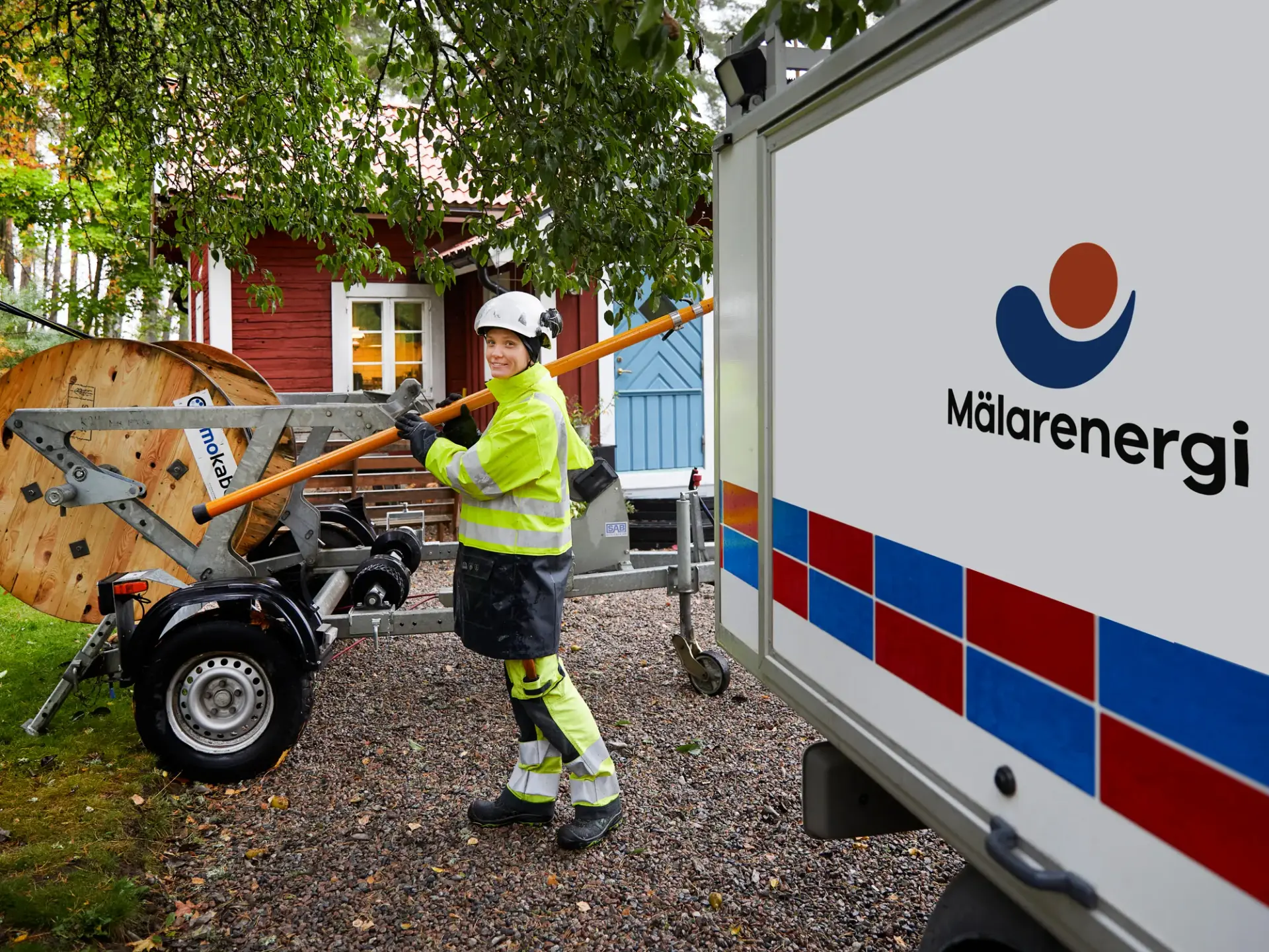 En kvinna i gul jacka arbetar med elledningar.