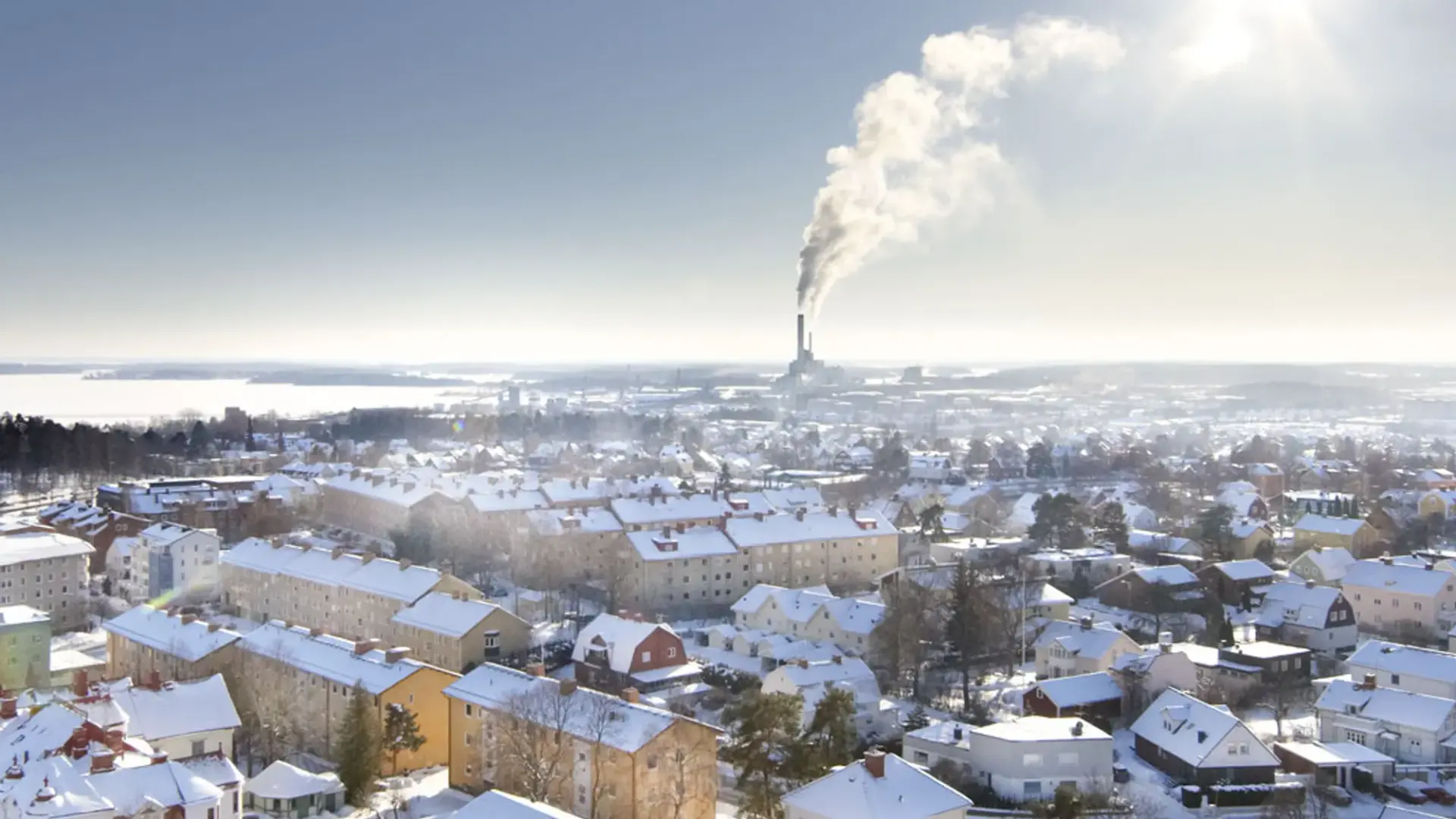 En utsikt över en snöig stad med en fabrik i fjärran.
