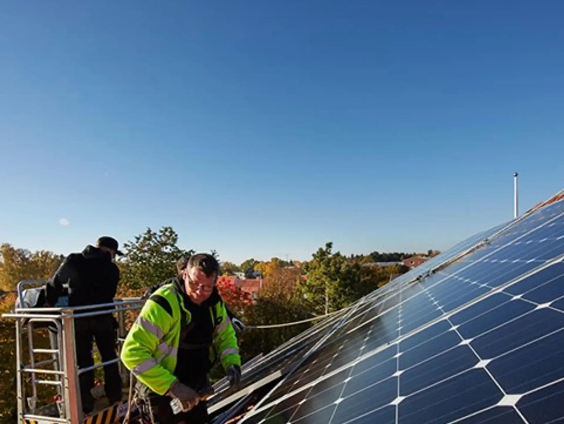 En man installerar solceller på taket till ett hus.