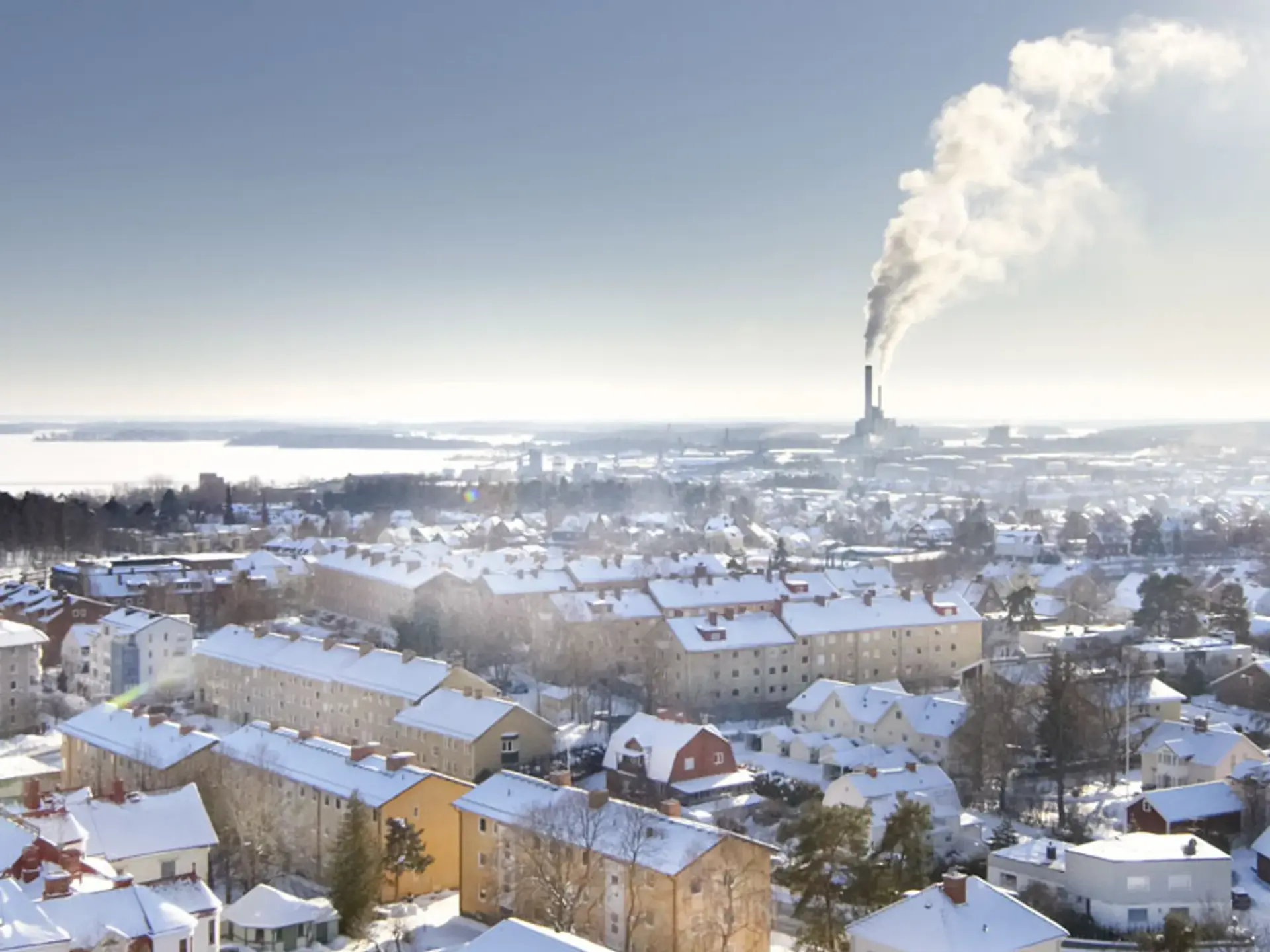 En utsikt över en snöig stad med en fabrik i fjärran.